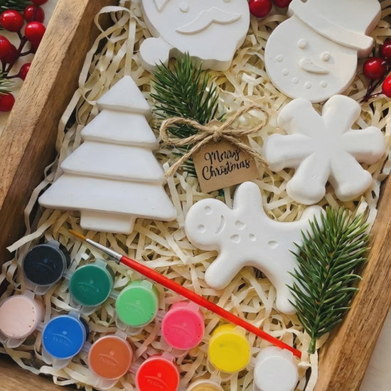 Open Playloom Christmas craft kit box with "North Pole Mail" letter and "Hey Playloom Parent" welcome card, alongside paints and ceramic ornaments.