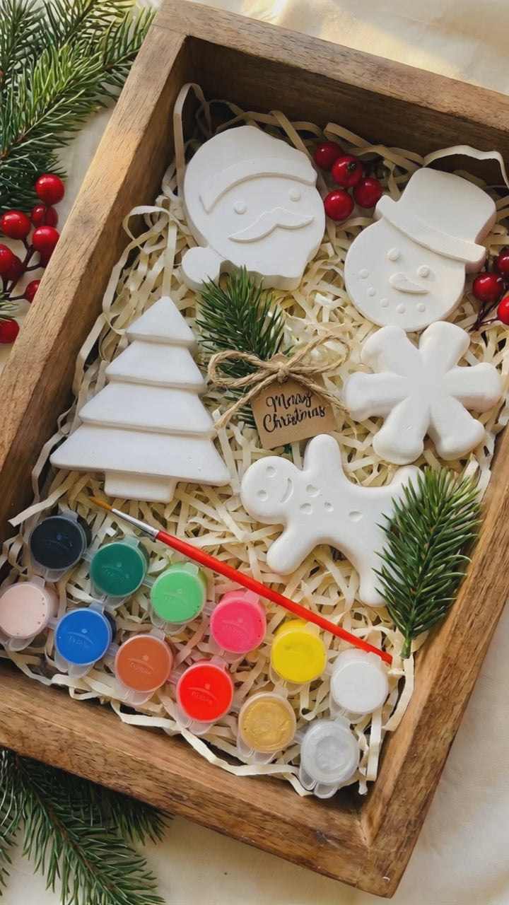 Open Playloom Christmas craft kit box with "North Pole Mail" letter and "Hey Playloom Parent" welcome card, alongside paints and ceramic ornaments.